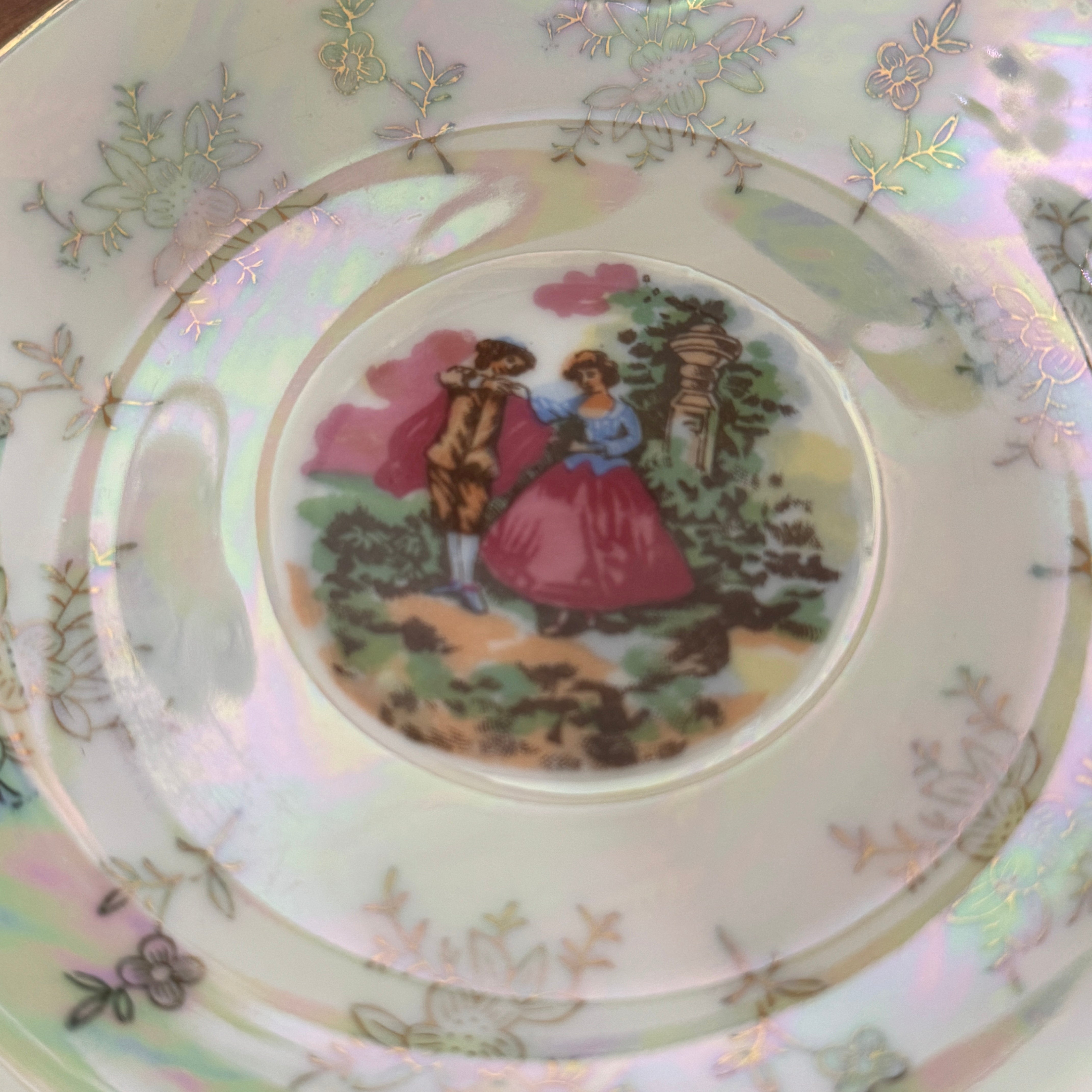 Decorative plate with a couple in a garden scene on a pastel background