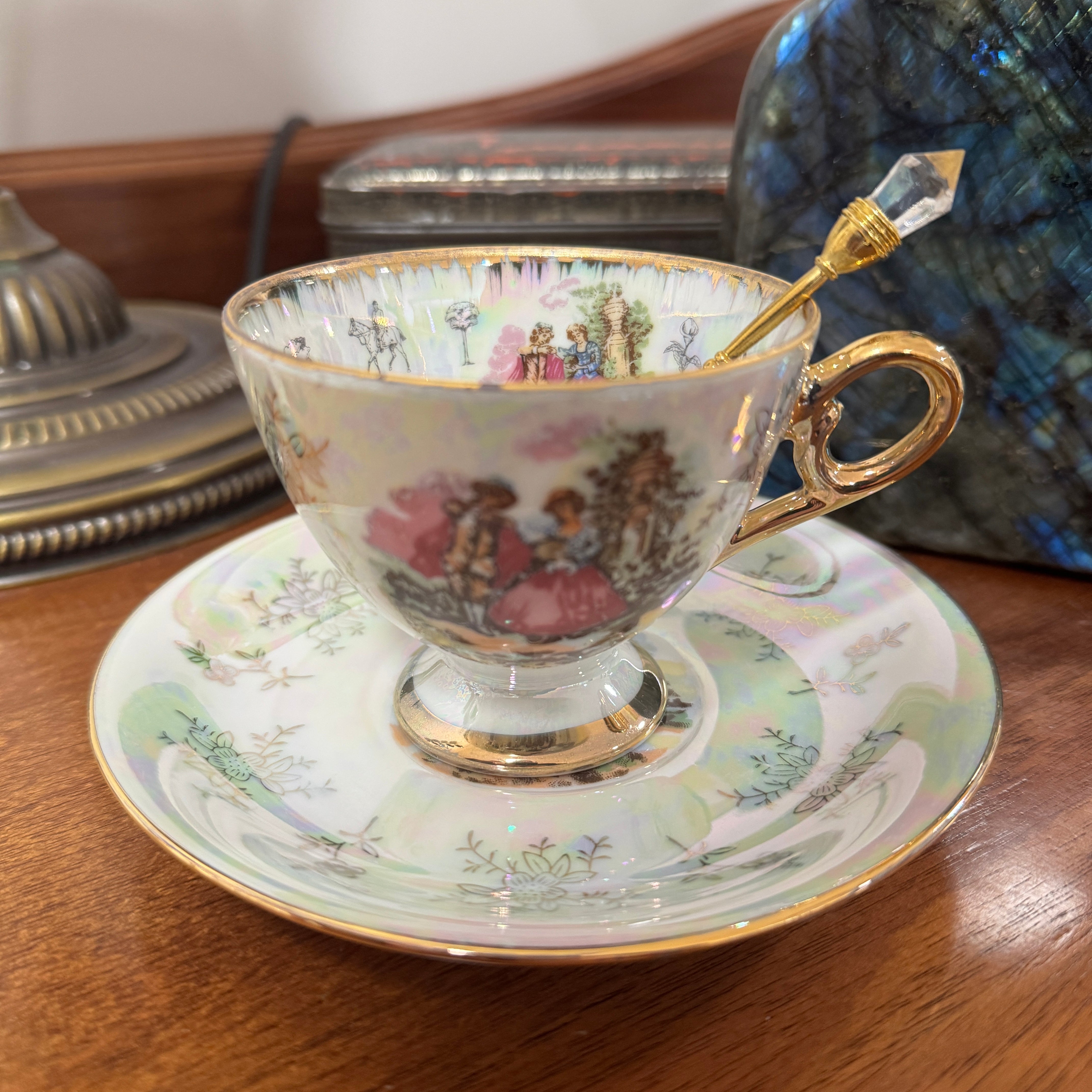 Decorative teacup and saucer with intricate designs on a wooden surface.