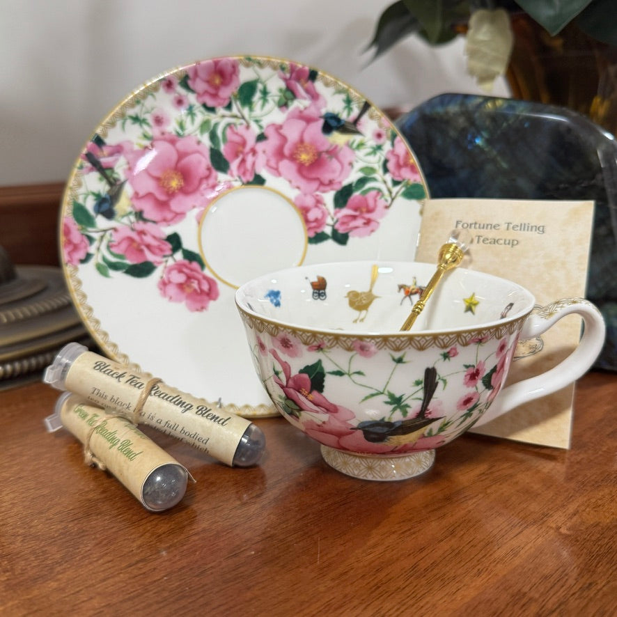 Floral teacup and saucer with tea bags and a card on a wooden surface