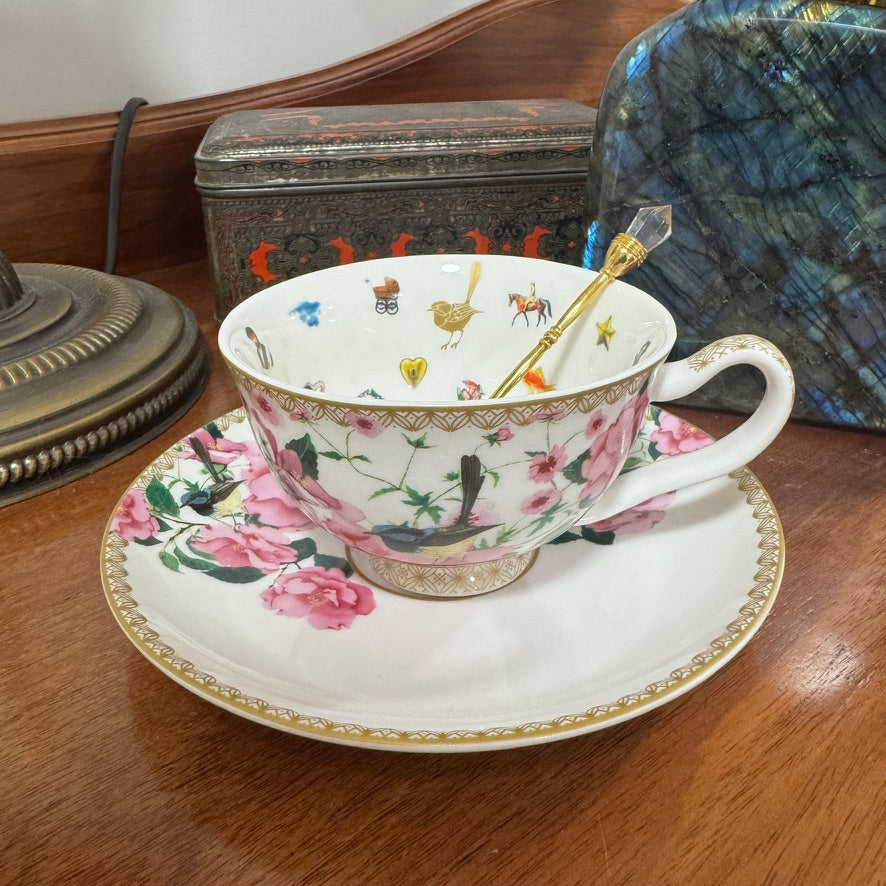 Decorative teacup with floral and bird pattern on a wooden surface