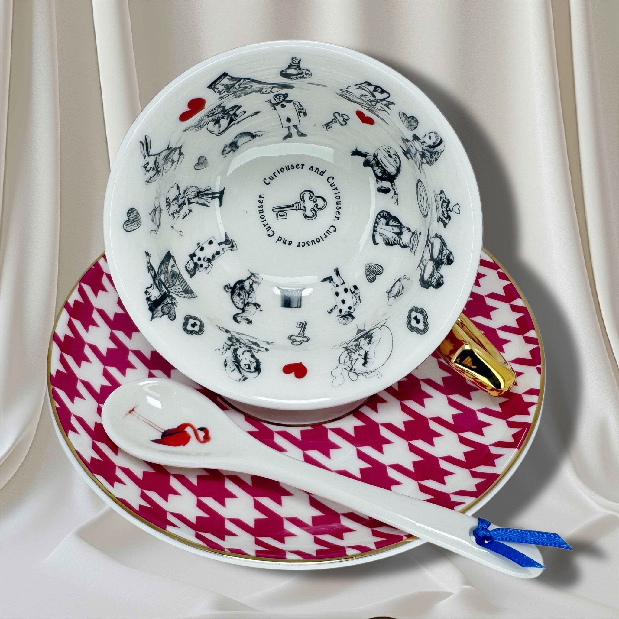 Deep pink houndstooth teacup with gold handle and Alice in Wonderland characters inside, on a matching saucer