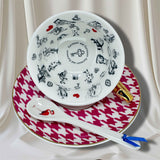 Deep pink houndstooth teacup with gold handle and Alice in Wonderland characters inside, on a matching saucer