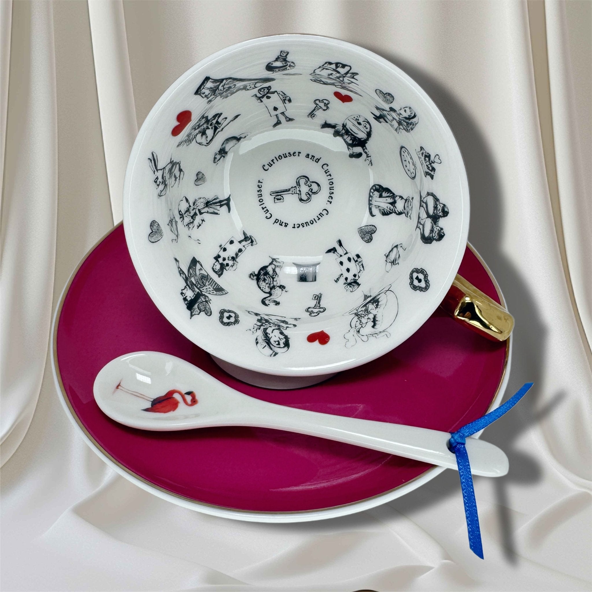Close-up of teacup interior with Alice in Wonderland fortune telling imagery and 'Curiouser and Curiouser' text.