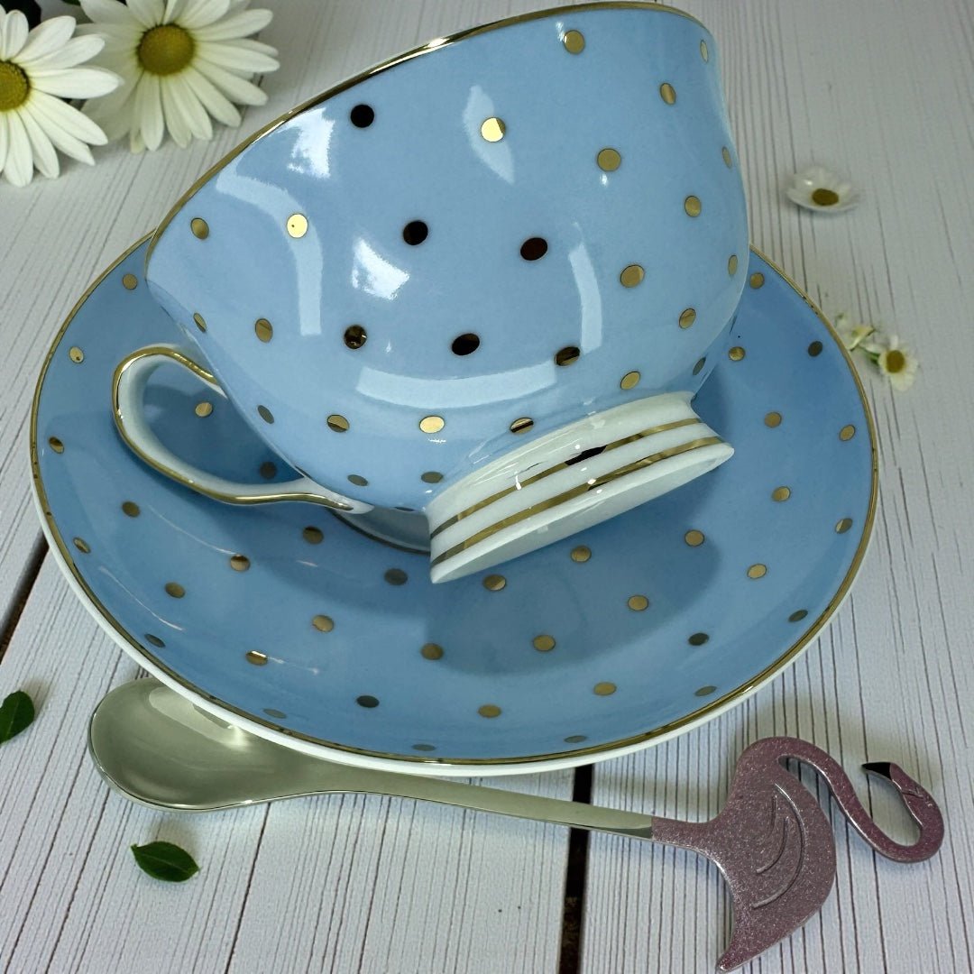 Close-up of the light blue polka dot teacup and saucer with the spoon, showing the cup's exterior and the Alice in Wonderland illustration detail