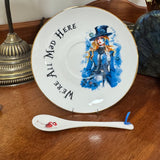 Decorative plate with Alice in Wonderland character design and a matching spoon on a wooden surface.