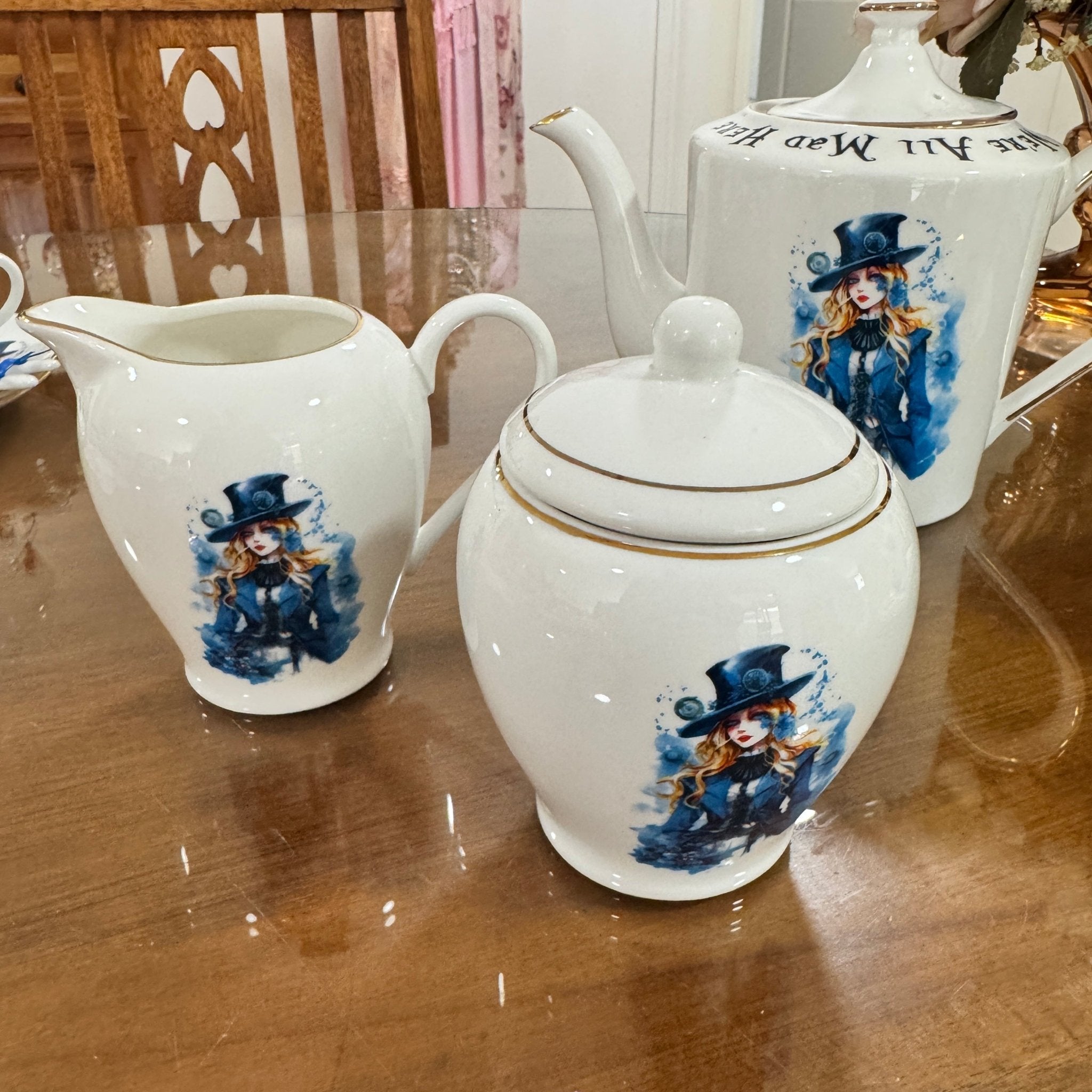Set of white ceramic teapots with decorative designs on a wooden table.