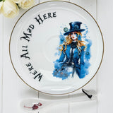 Detailed shot of the 'We're All Mad Here' Teacup Saucer, showing the Mad Hatter female portrait and gold trim.