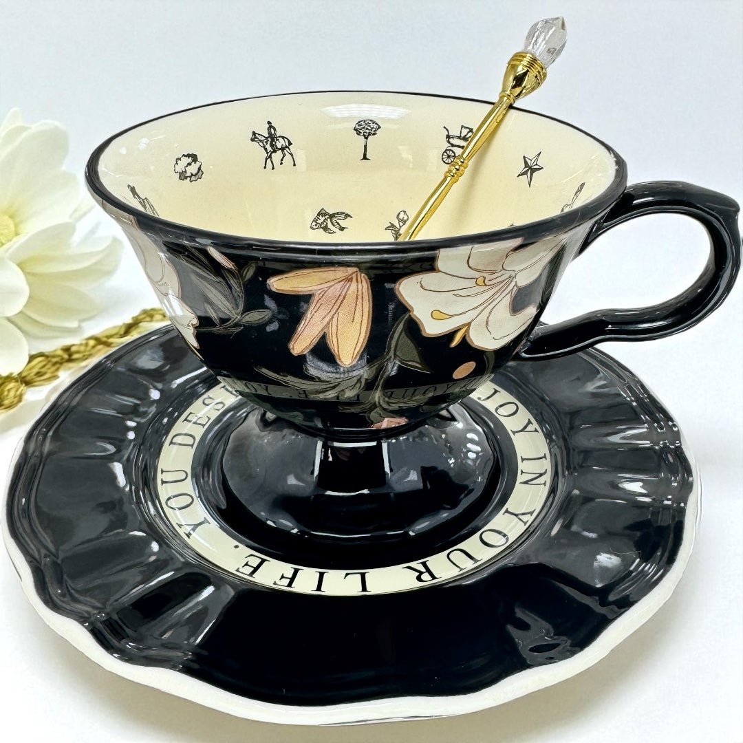Black teacup with floral design on a matching saucer, accompanied by white flowers.