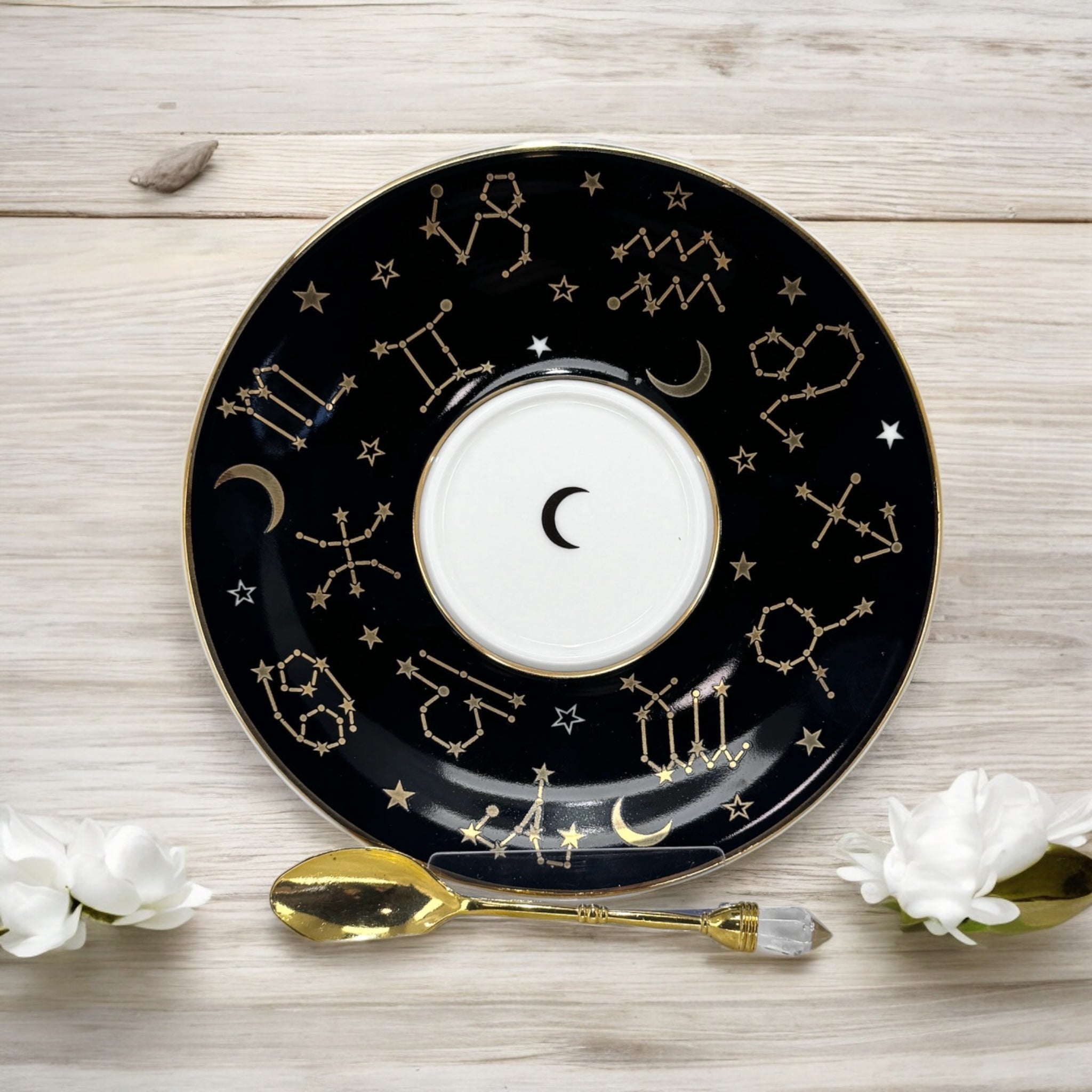 Black tarot-themed teacup and saucer set with mystical tarot symbols inside, accompanied by a symbol guidebook and a gold teaspoon, ideal for daily tea leaf reading and divination