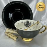 Teacup with gold handle and black saucer on a silver background