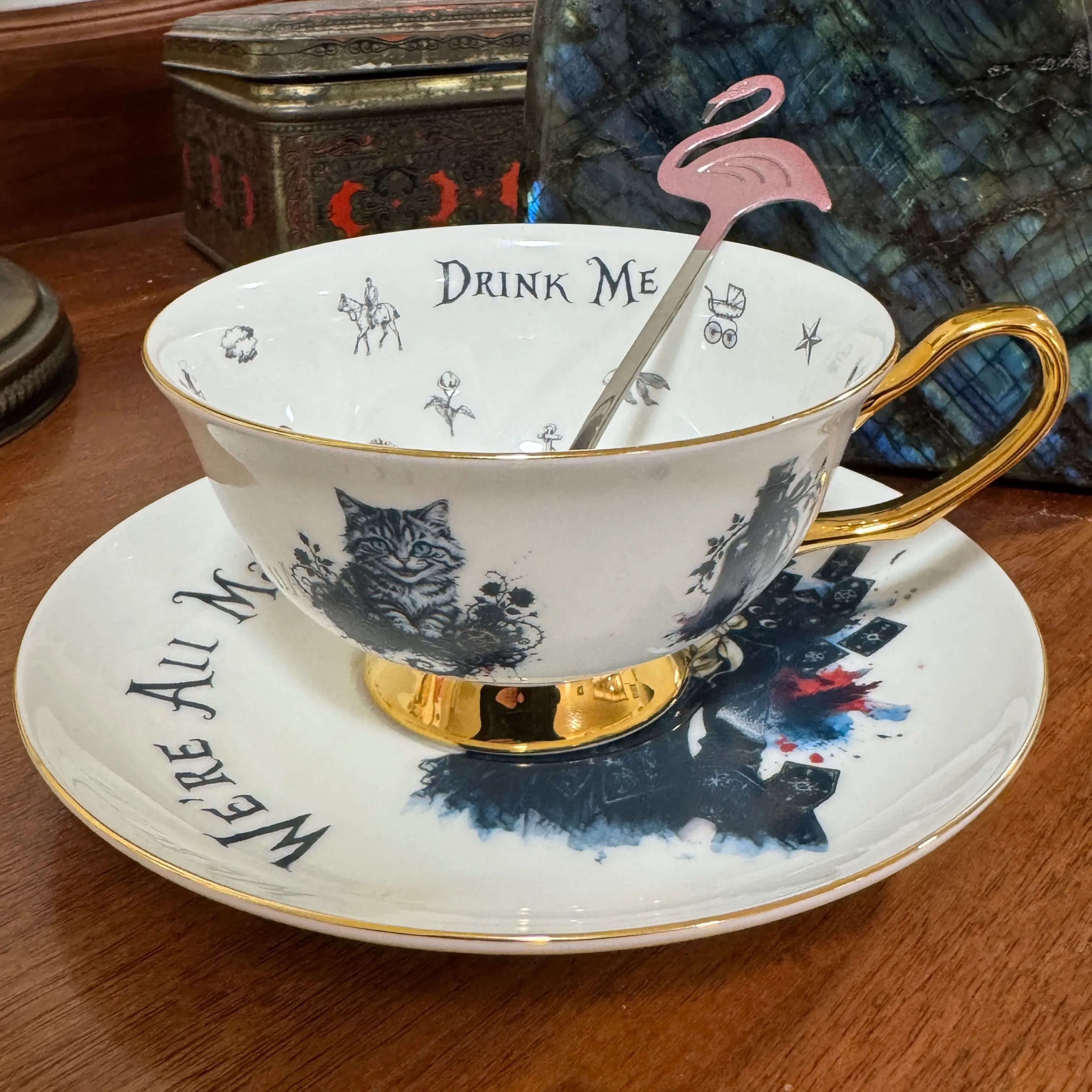 Gothic Alice teacup on its saucer showing the Cheshire Cat, Drink Me inside the rim and a 24ct gold handle