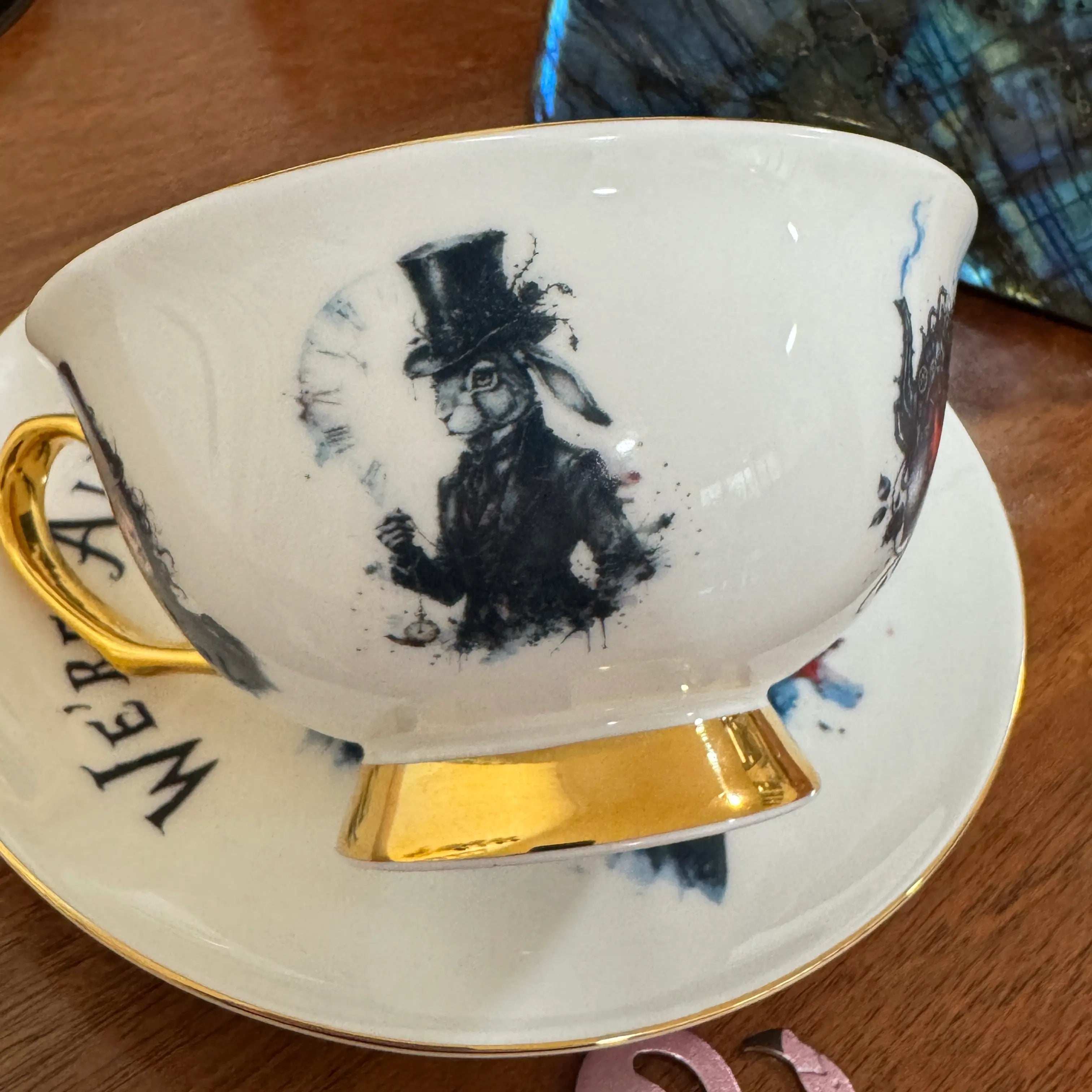 White Rabbit in a top hat holding a pocket watch in front of a clock face on the gothic Alice teacup