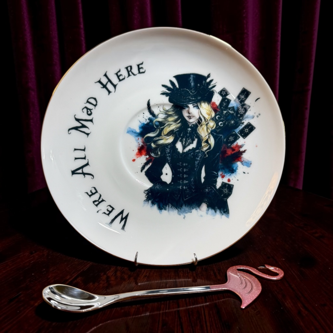 Gothic Alice saucer with top hat, tarot cards and We're All Mad Here lettering, with pink flamingo teaspoon
