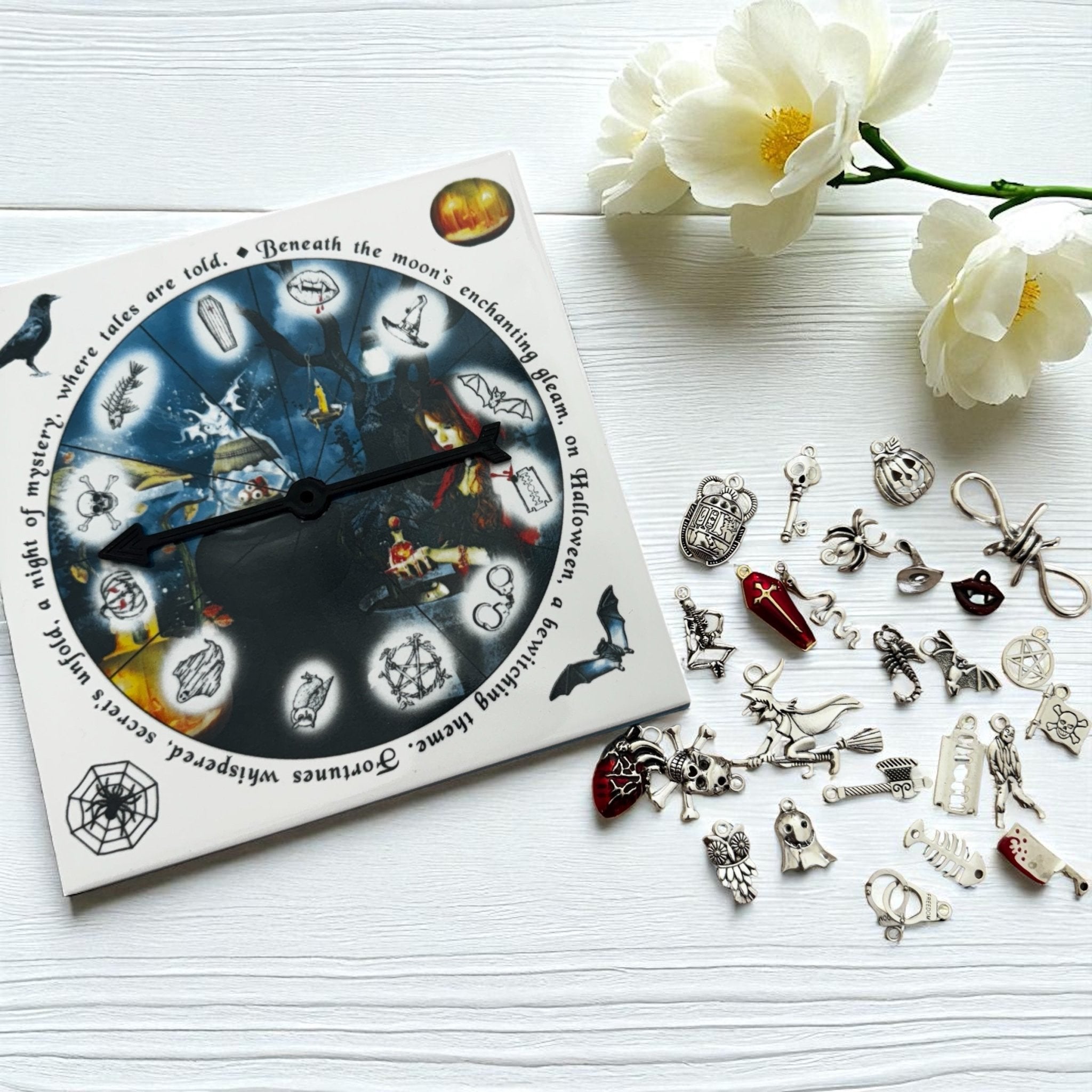 Collection of Halloween-themed charms on a white surface with a decorative box and flowers.