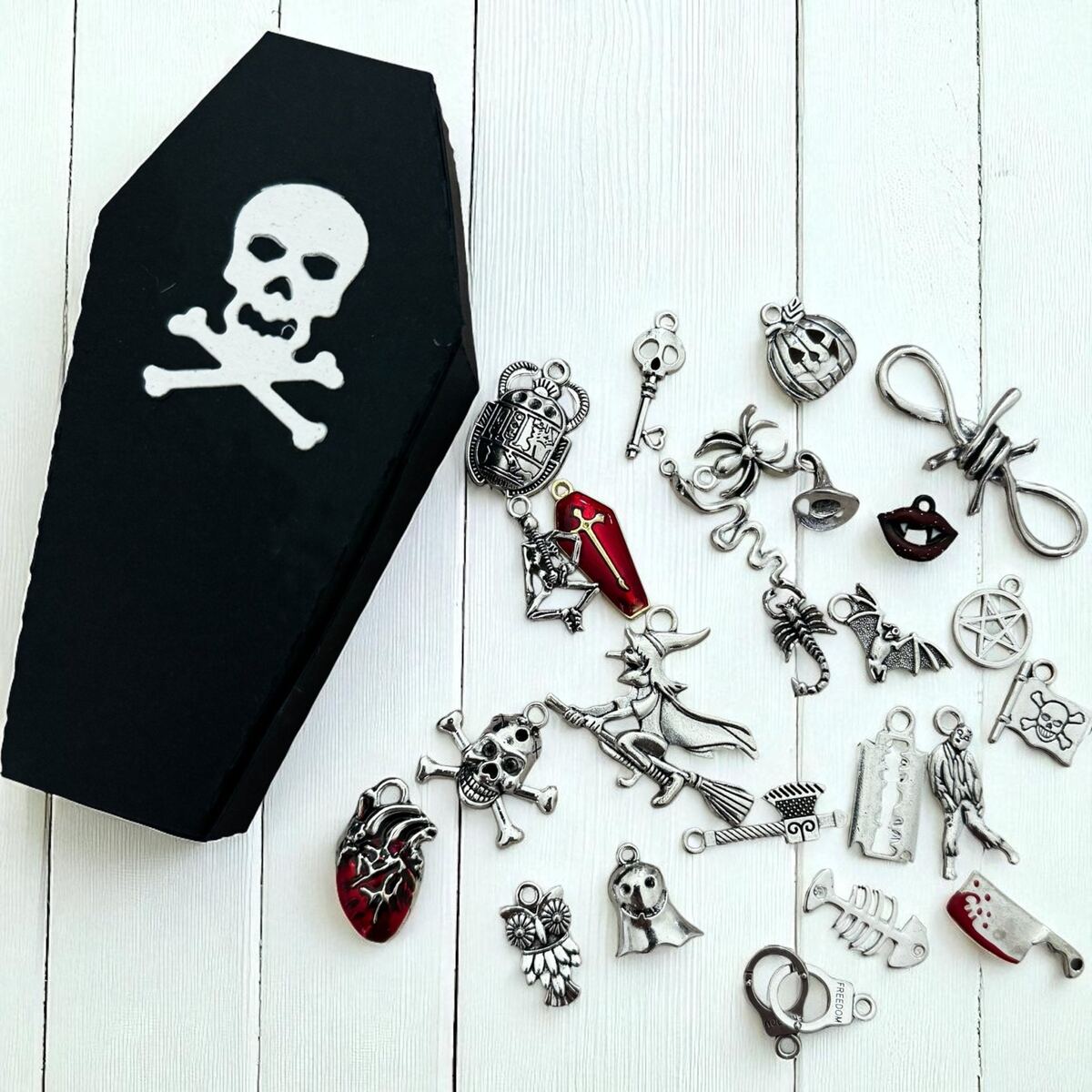 Black coffin-shaped box with skull design surrounded by various Halloween-themed charms