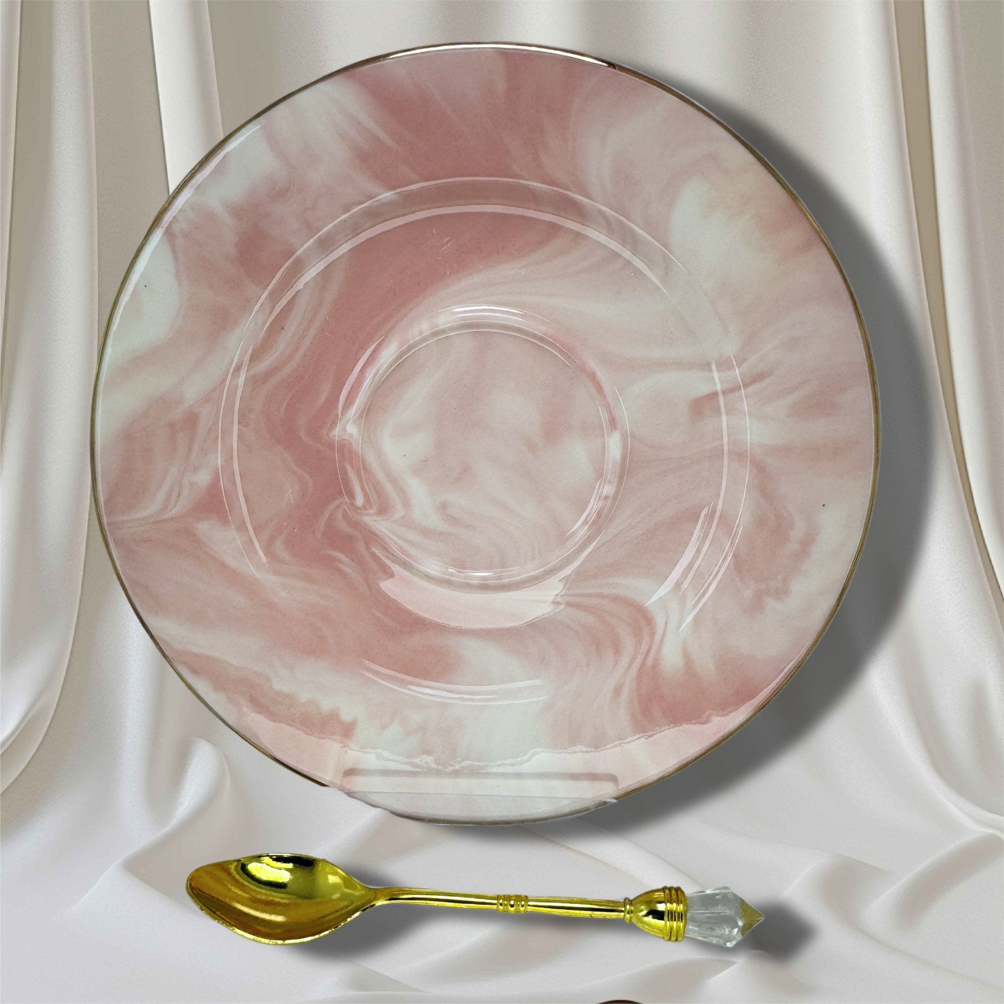Pink and white marble-effect saucer with a gold rim and a gold teaspoon with a clear crystal accent.