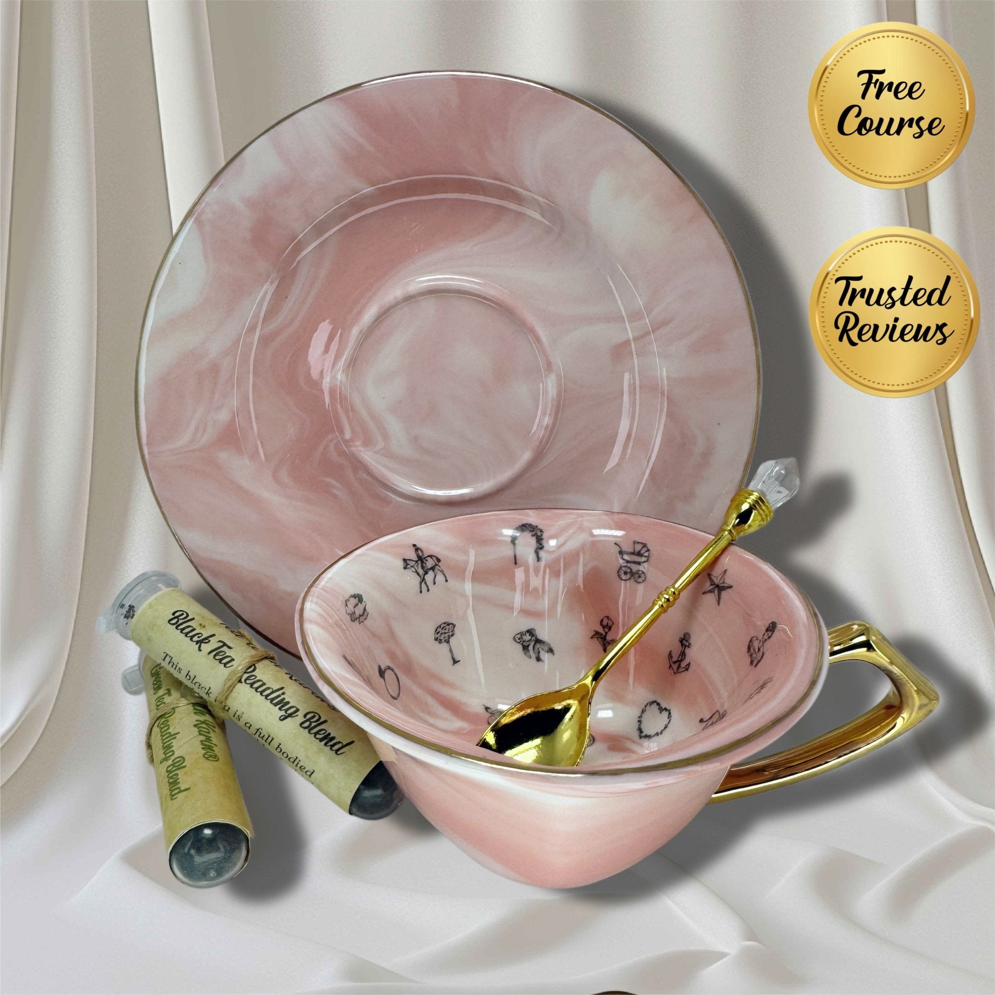 Pink marble-effect teacup and saucer set with a gold spoon and two 'Black Tea Reading Blend' sample tubes on white satin
