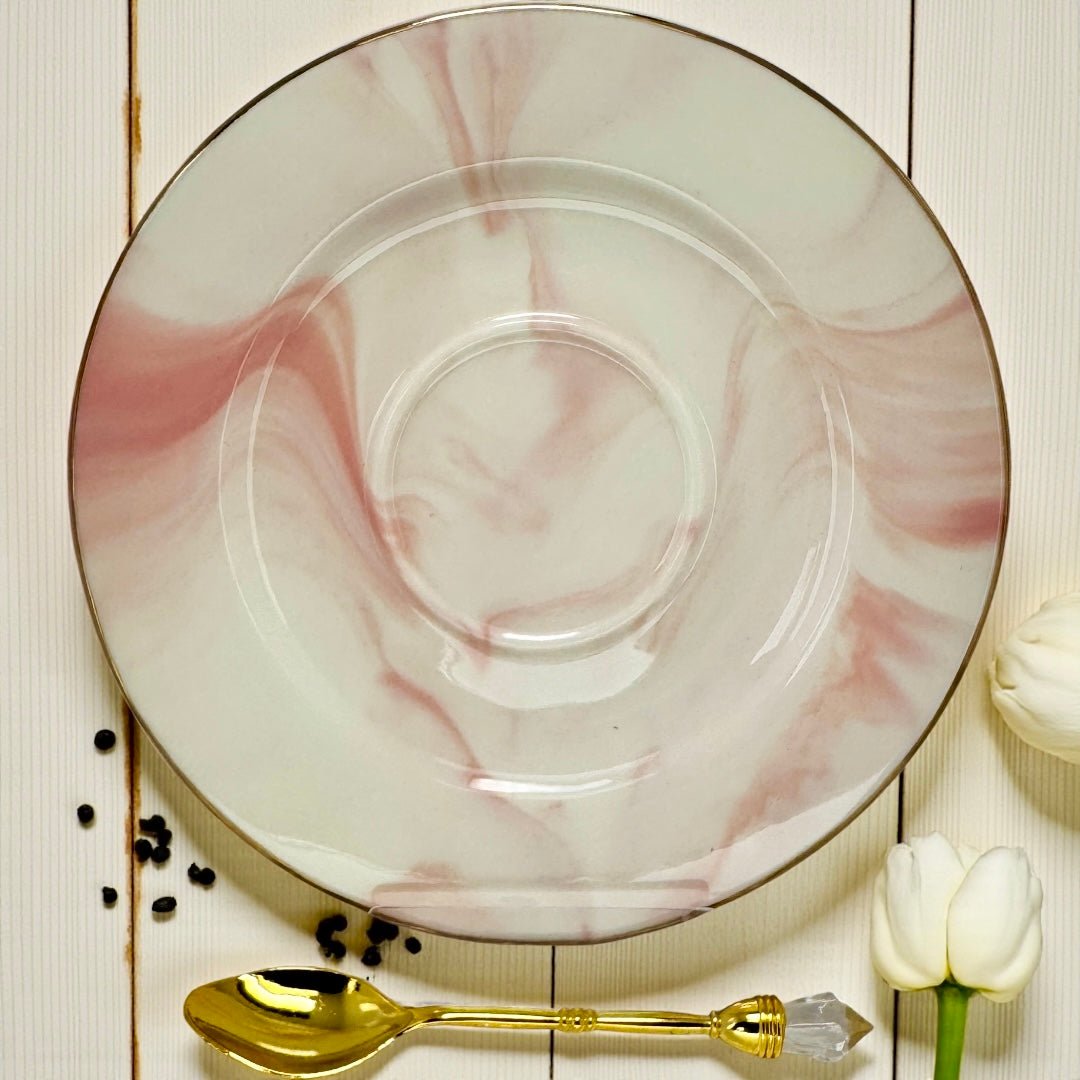 Pink and white marble-effect saucer with a gold rim and a gold teaspoon with a clear crystal accent.