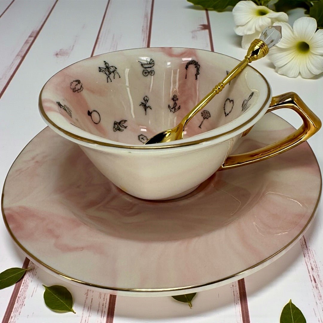 White teacup on its side, showing the internal black line drawings of fortune telling symbols like a crescent moon, dog, house, and ring.