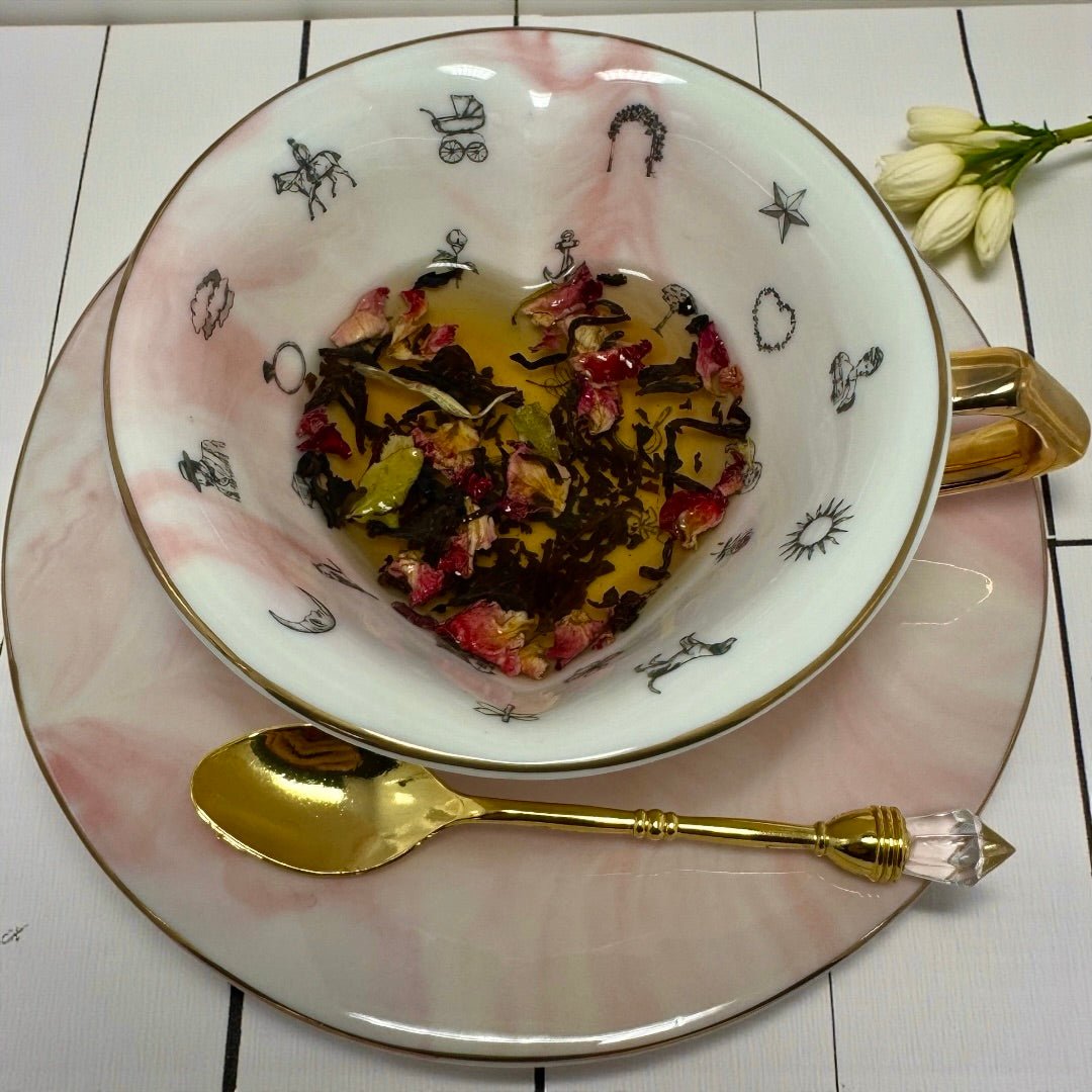 Overhead view of teacup and saucer with heart-shaped tea leaves, including rose petals, ready for tasseography.