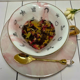 Overhead view of teacup and saucer with heart-shaped tea leaves, including rose petals, ready for tasseography.