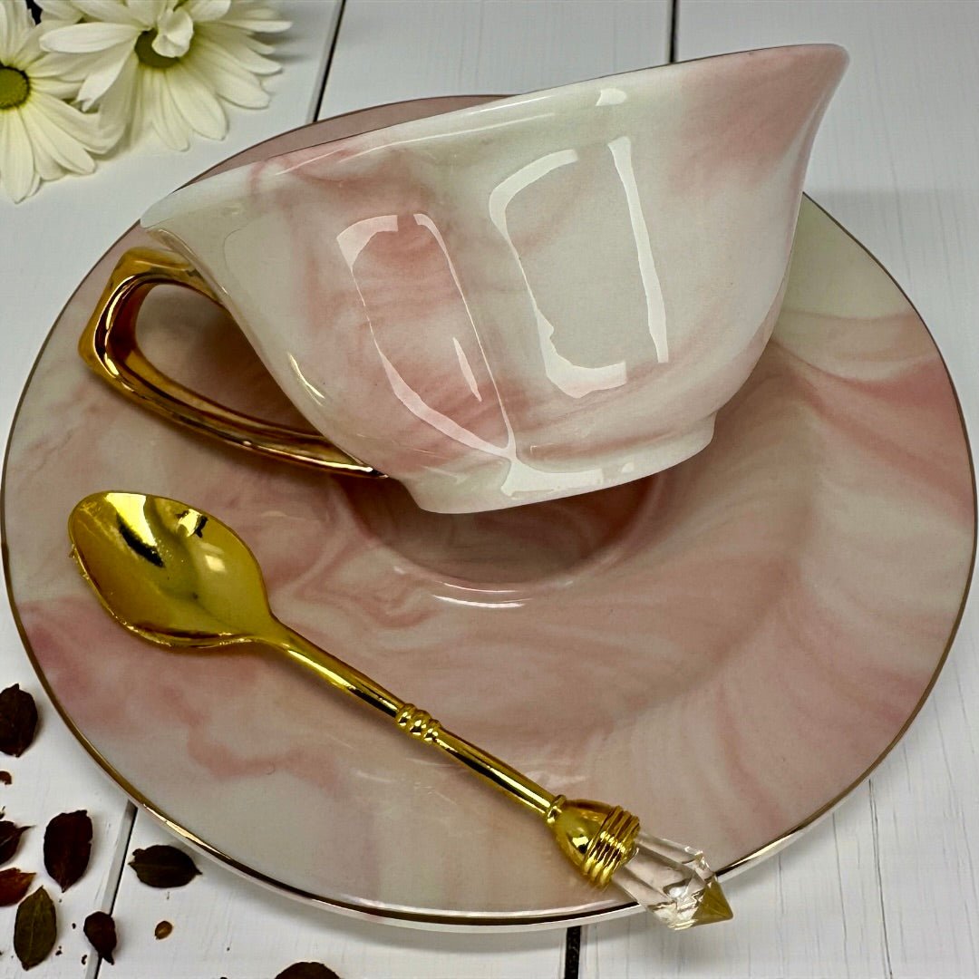 Pink marble teacup and saucer set with gold handle and rim, displaying the internal fortune telling symbols
