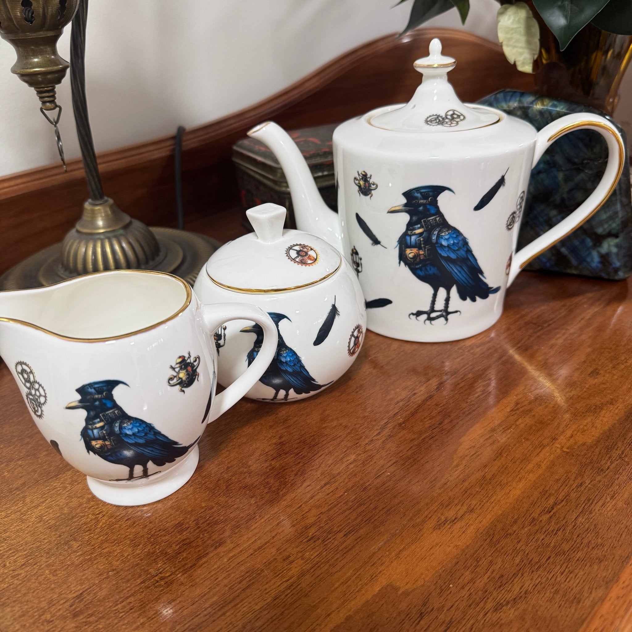Steampunk Crow Tea Party Set — full raven tea set with 24CT gold teapot, sugar bowl and creamer jug on wooden surface | Tea Leaf Reader