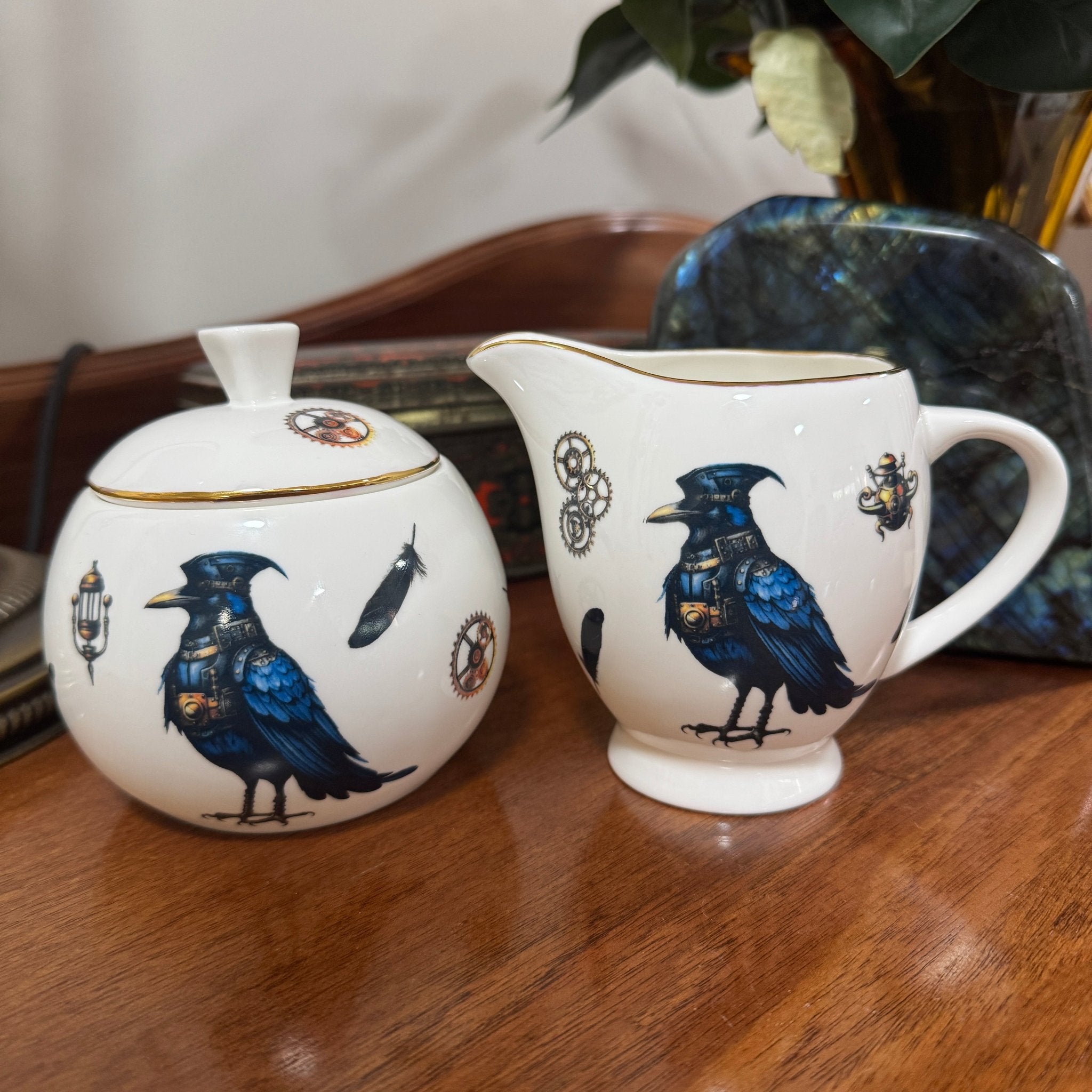 Steampunk Crow Tea Party Set — close-up of 24CT gold raven sugar bowl and creamer jug with blue bird design on wooden surface | Tea Leaf Reader