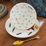 Crow King Tea Leaf Reading Cup — inside view showing tasseography symbols with feather and gothic motifs, gold spoon on wooden surface | Tea Leaf Reader
