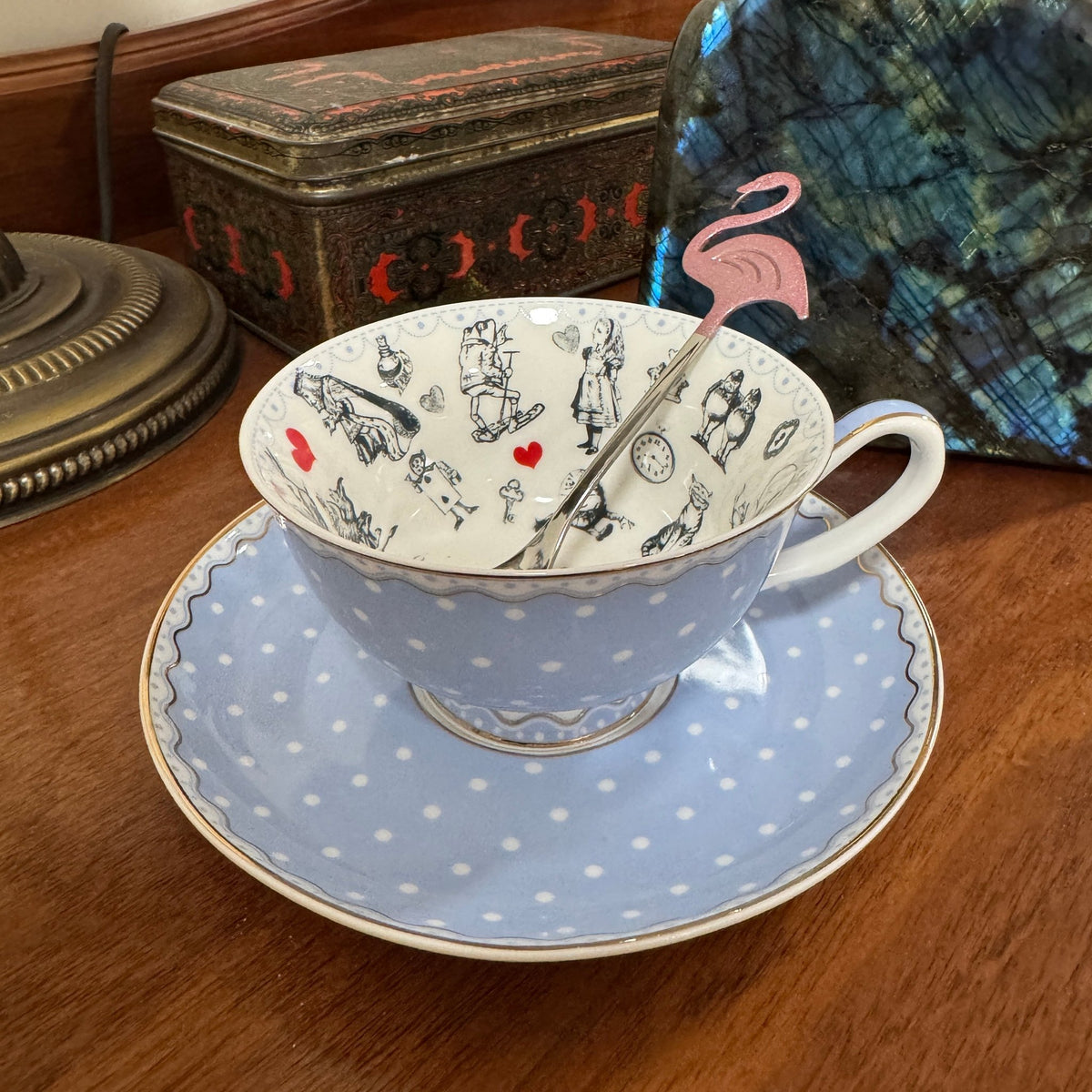 Pale blue Alice in Wonderland teacup resting on its white spotted saucer
