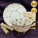 Tea cup with black tea packaging and a saucer on a purple fabric background