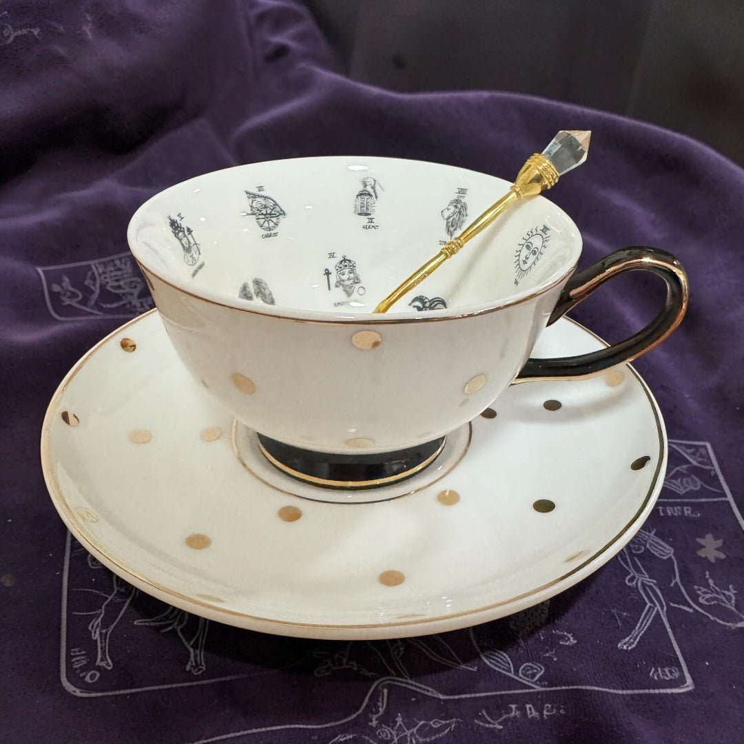 Teacup with gold polka dots on a matching saucer, placed on a purple fabric background.