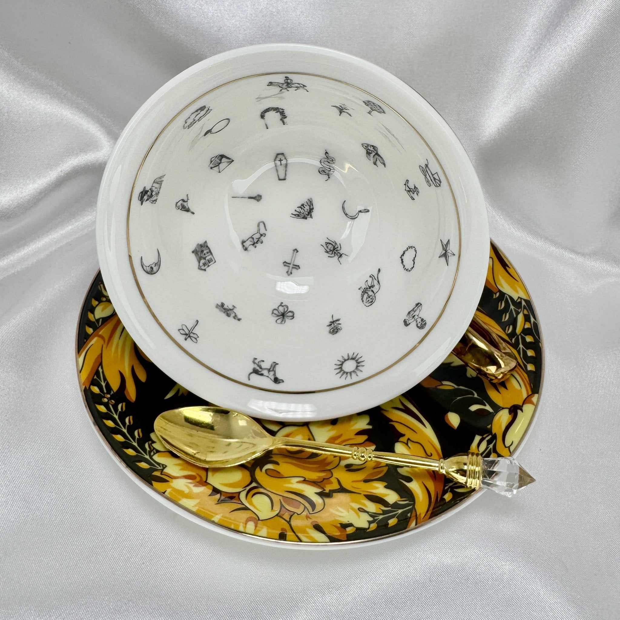 Overhead view of white teacup interior showing black illustrations for tasseography fortune telling symbols