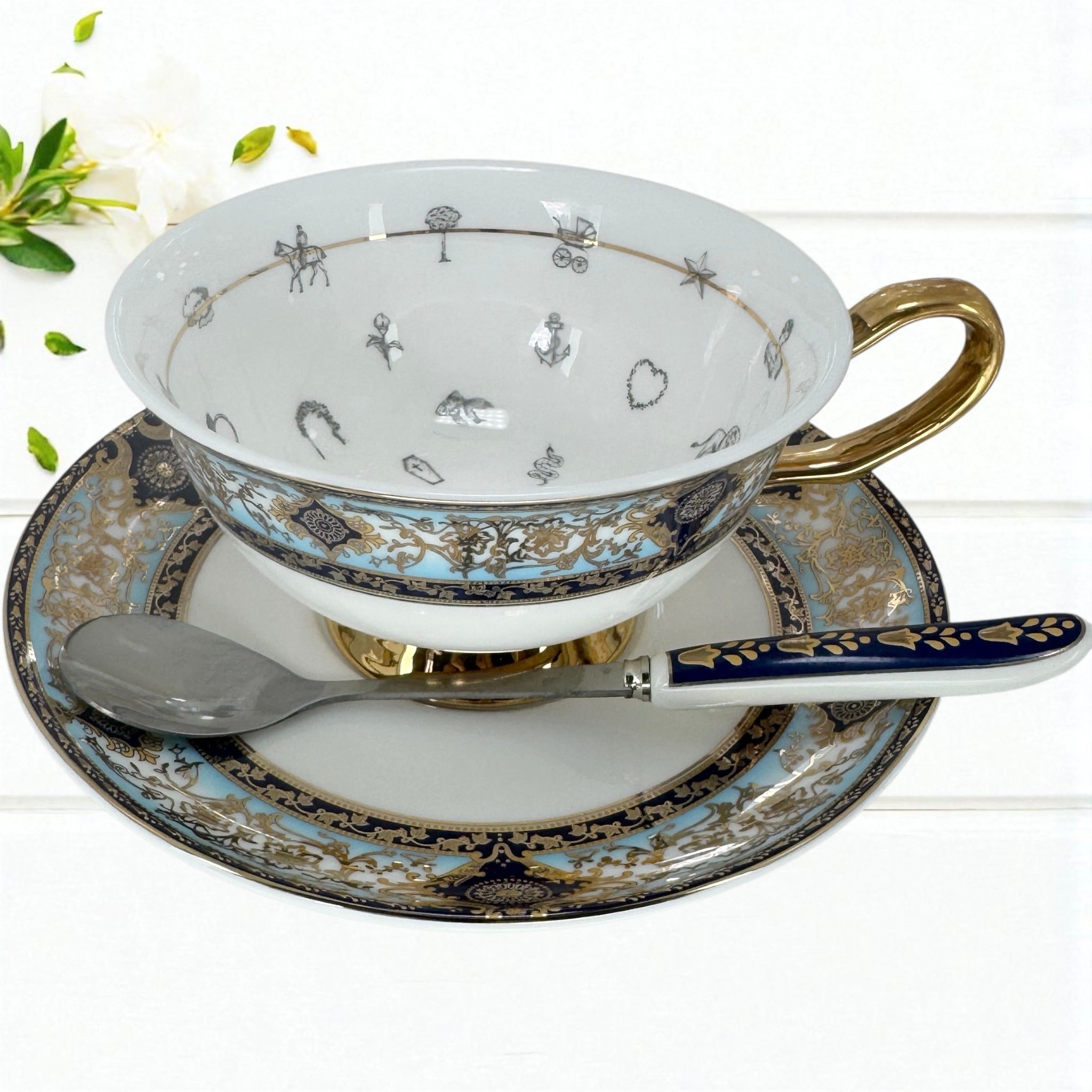 Tea cup, saucer, and spoon with decorative patterns on a white background