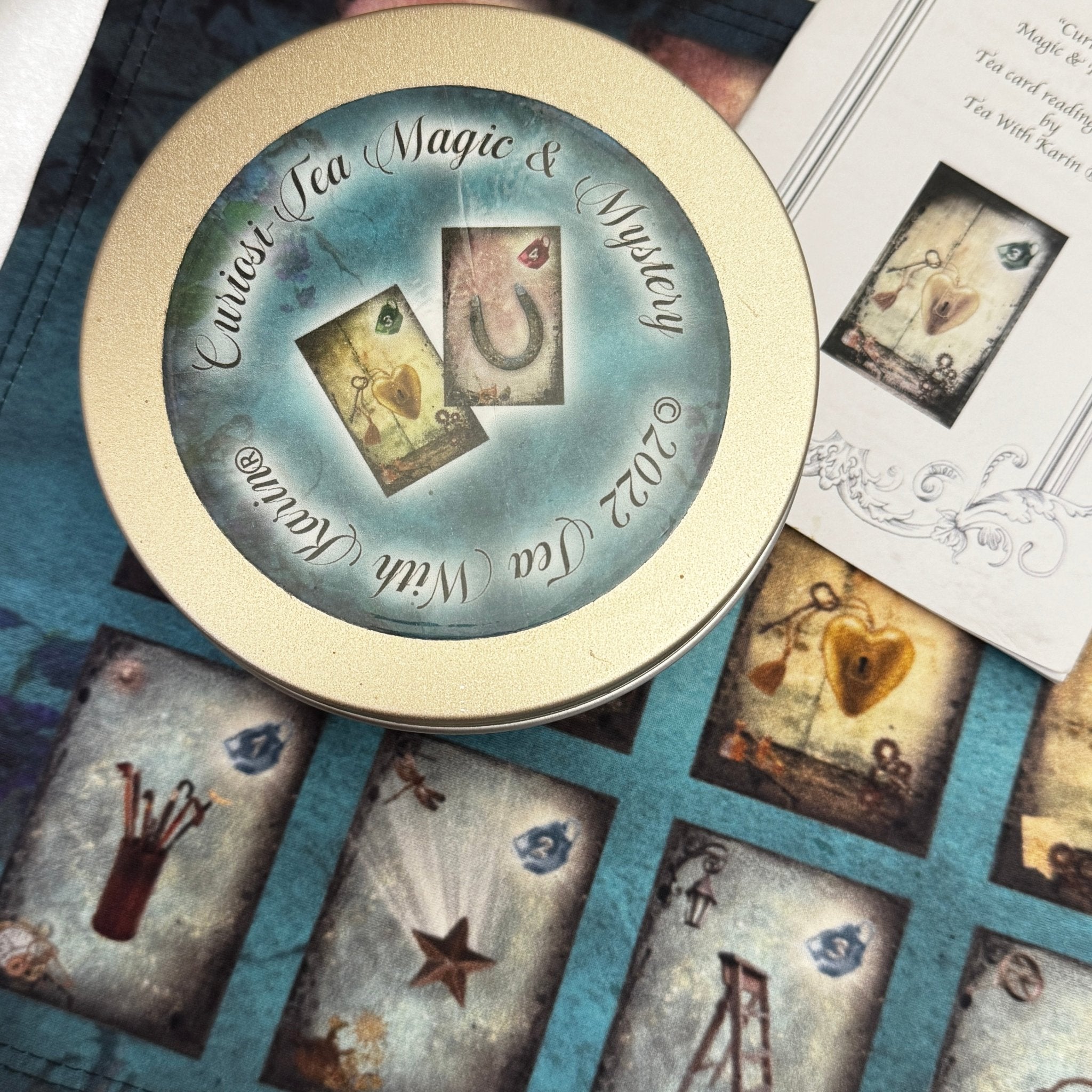 Discover the Curiosi-Tea Oracle Kit – a compact and enchanting tool for tea leaf divination. This unique set includes 18 thoughtfully designed cards, each adorned with symbolic imagery to guide your readings. Accompanied by a selection of charms, the kit offers a tactile dimension to your divination practice. Housed in a sleek gold tin, it’s perfect for on-the-go insights or intimate sessions at home. 