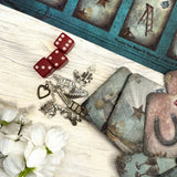 Discover the Curiosi-Tea Oracle Kit – a compact and enchanting tool for tea leaf divination. This unique set includes 18 thoughtfully designed cards, each adorned with symbolic imagery to guide your readings. Accompanied by a selection of charms, the kit offers a tactile dimension to your divination practice. Housed in a sleek gold tin, it’s perfect for on-the-go insights or intimate sessions at home. 