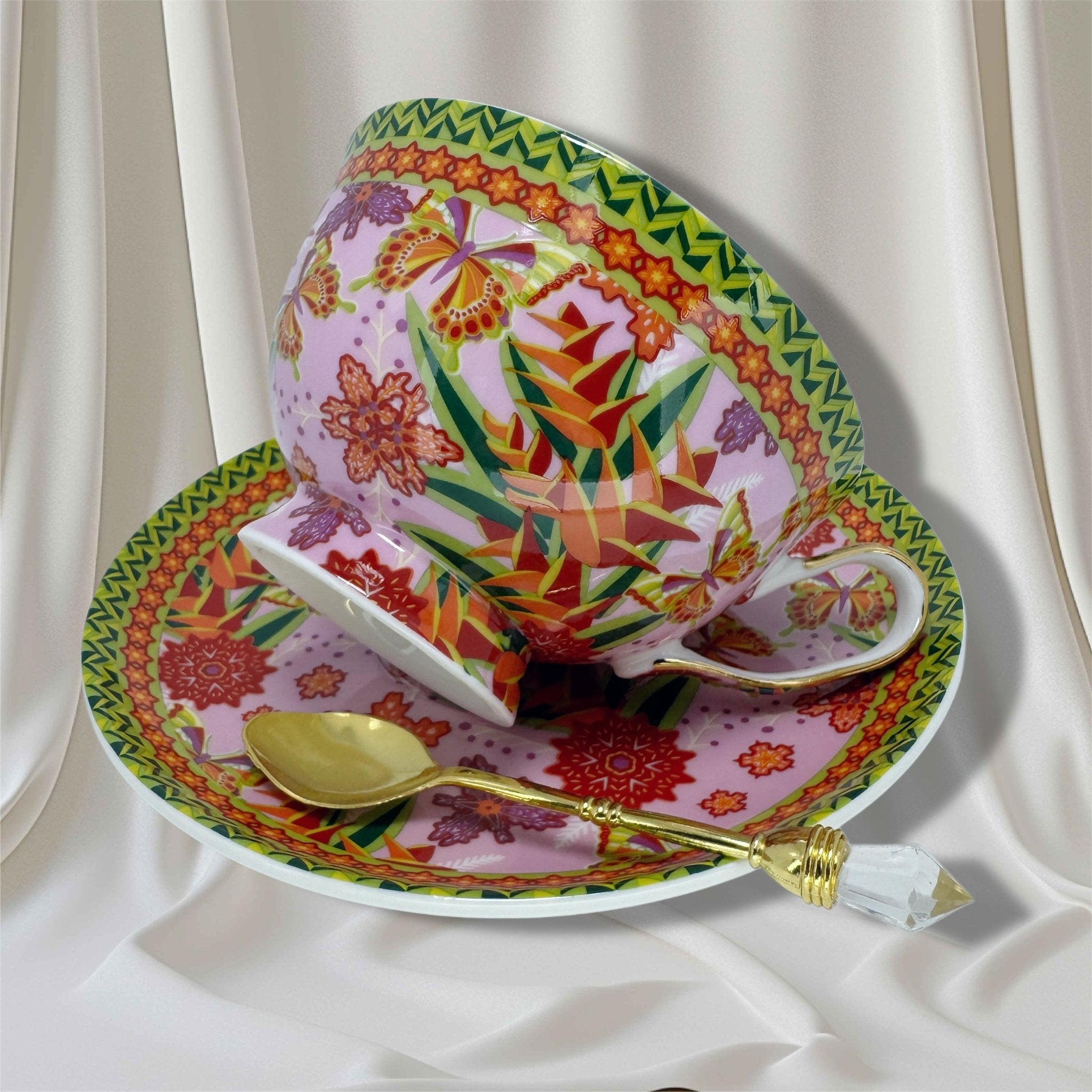 Right-side view of floral and butterfly teacup and saucer set with a gold crystal-handled spoon.