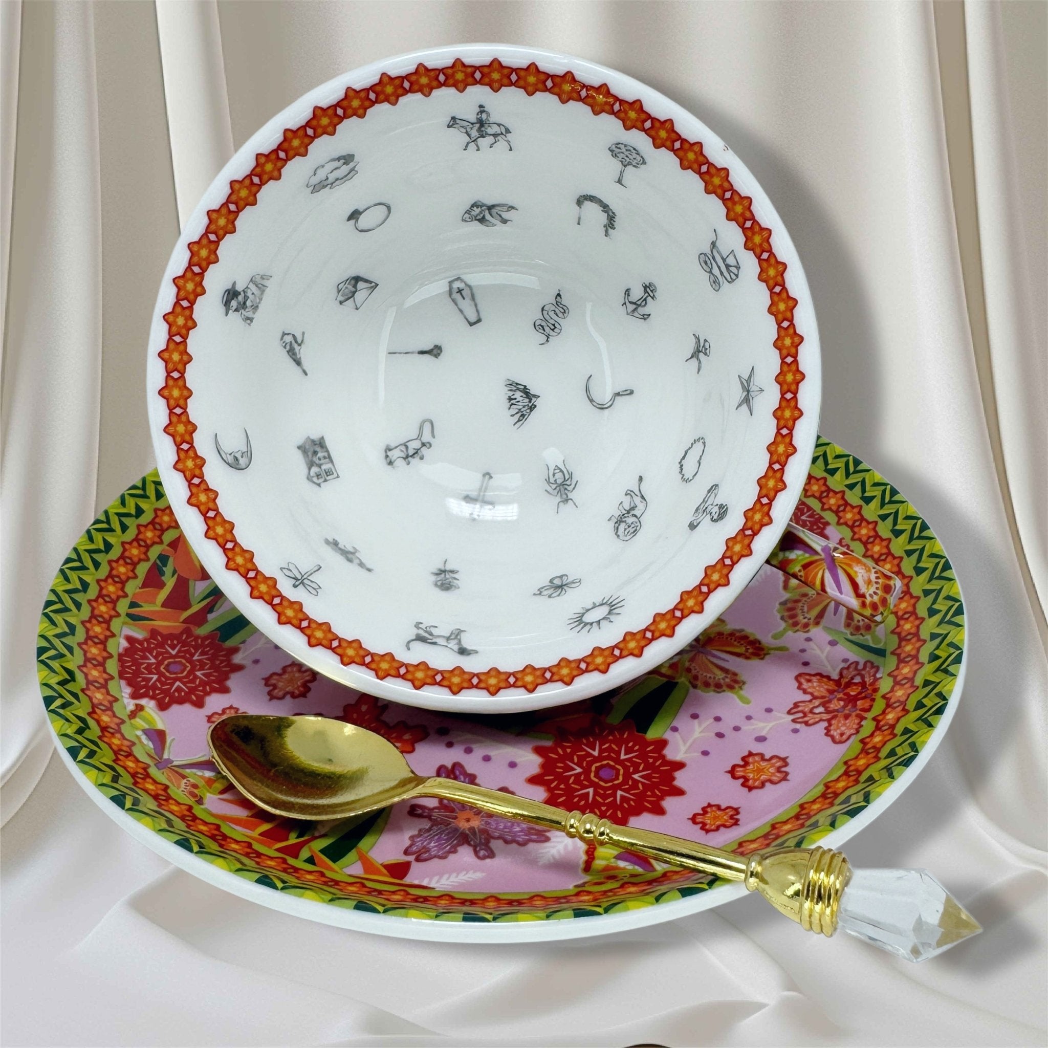 Tasseography cup tipped on saucer, revealing internal black line drawings of fortune symbols