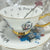 Video view Alice in Wonderland Punk style tea leaf reading Tea cup and saucer set with artistic design and text on a white surface.
