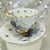 Spider motif wrapped around a white teacup, with delicate gold accents