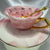 Video showcasing the pink marble-effect teacup and saucer set, rotating to display the gold handle and the full collection of black fortune-telling symbols inside the cup.