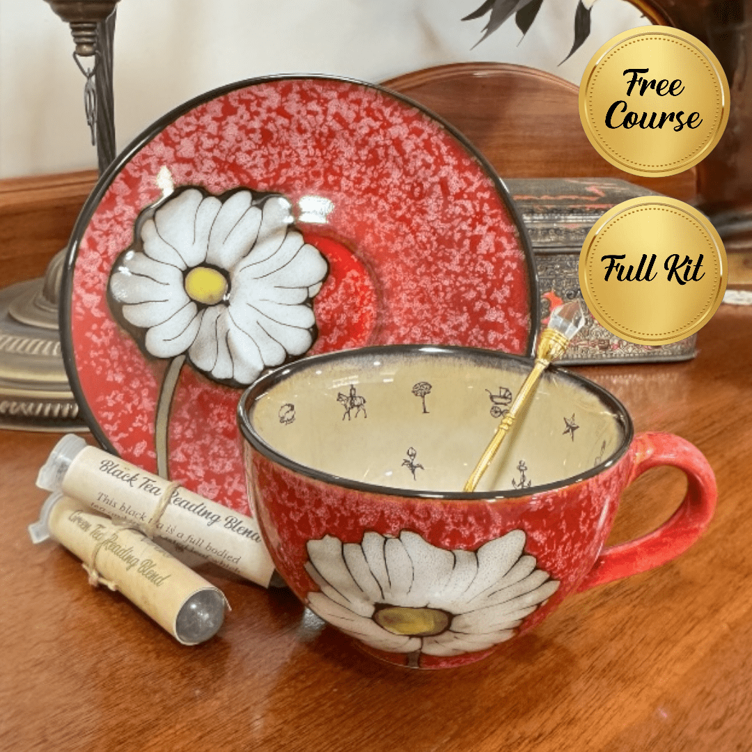 Red ceramic mug with floral design on a wooden surface, accompanied by a matching plate and tea packaging.