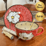 Red ceramic mug with floral design on a wooden surface, accompanied by a matching plate and tea packaging.