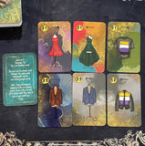 A beautiful 52-card tea leaf reading deck with vibrant watercolor-style illustrations, displayed alongside a soft cotton drawstring bag and a small gold teaspoon. 