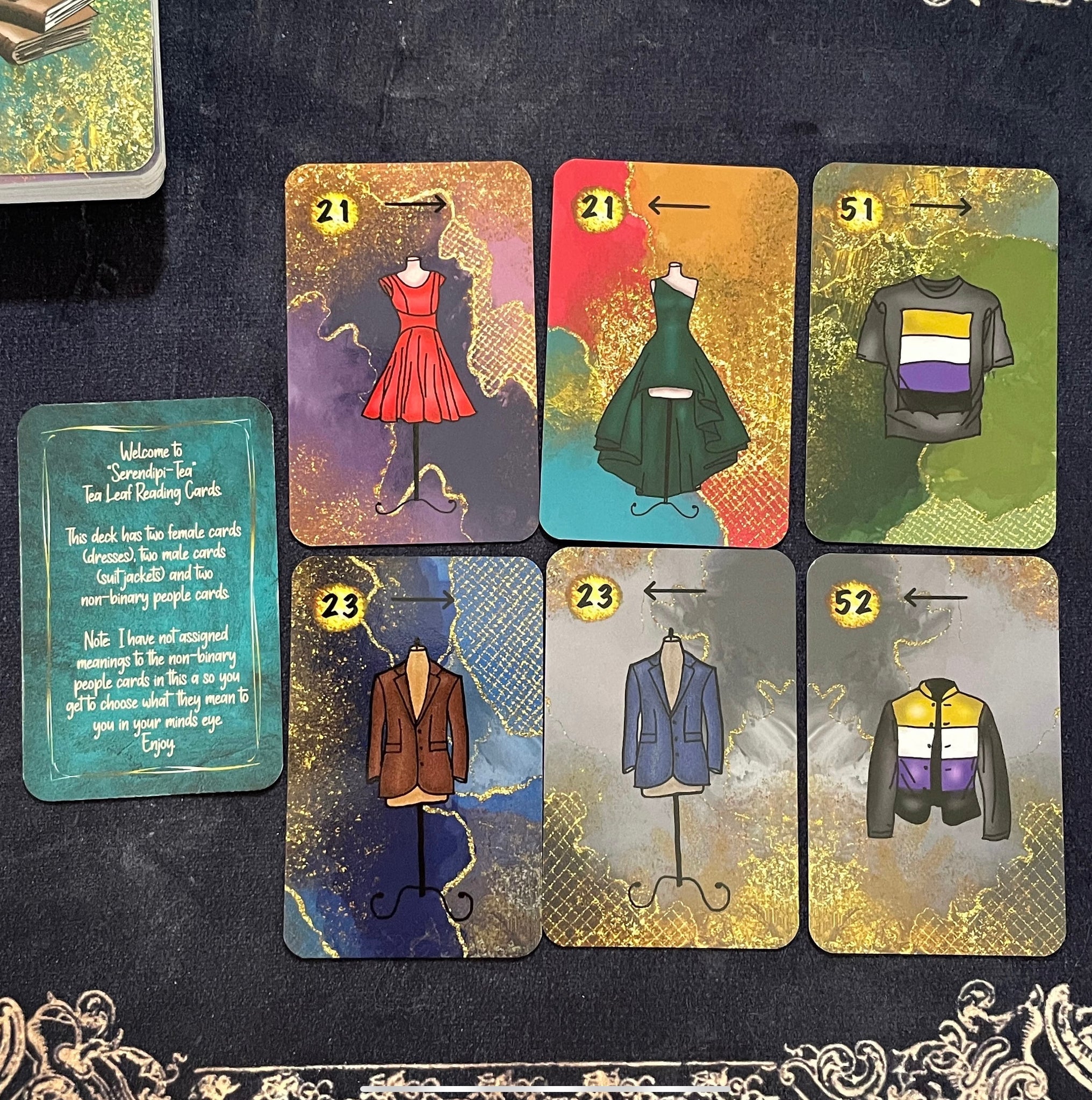 A beautiful 52-card tea leaf reading deck with vibrant watercolor-style illustrations, displayed alongside a soft cotton drawstring bag and a small gold teaspoon. 