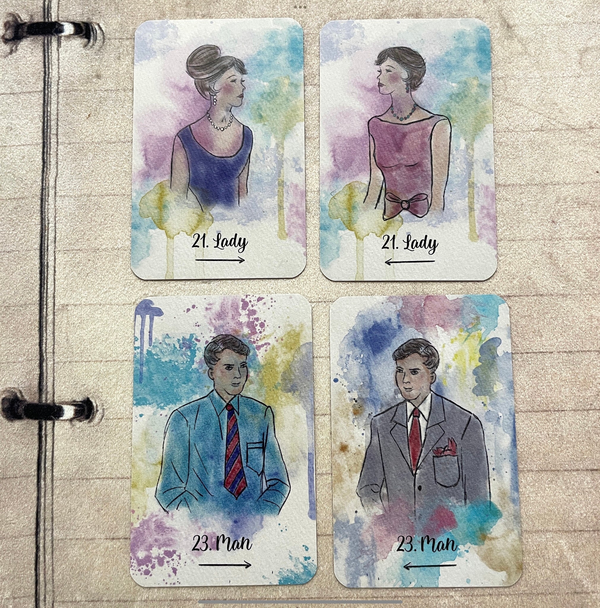 A soft watercolor deck titled “Sereni-Tea” with pen outline images, displayed in a spread showing vibrant, detailed cards.  