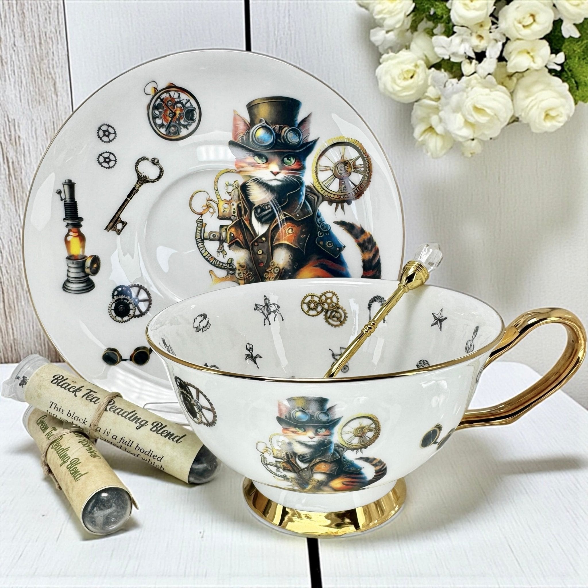 A close-up, eye-level view of a teacup and saucer set featuring a steampunk-style cat. The gold handle and spoon are prominent in the shot.