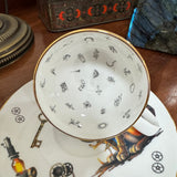 Teacup with decorative patterns on a matching saucer on a wooden surface.