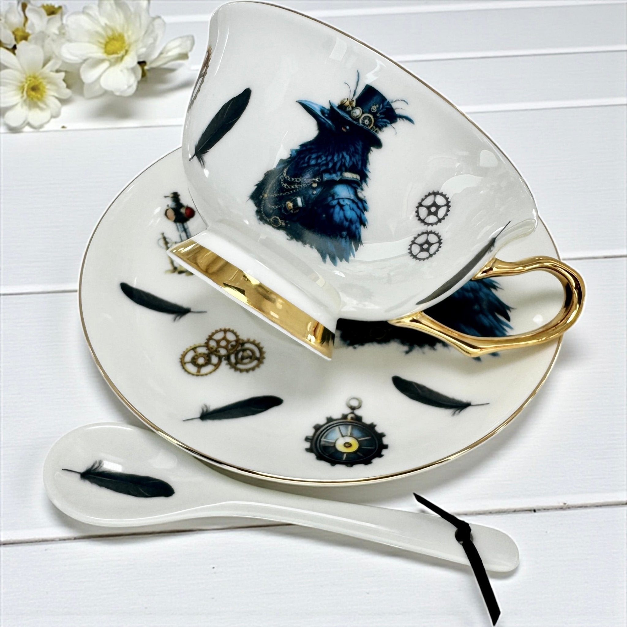 Close-up of the inside of the teacup, showing the steampunk crow, feathers, and clockwork designs, with a matching spoon.