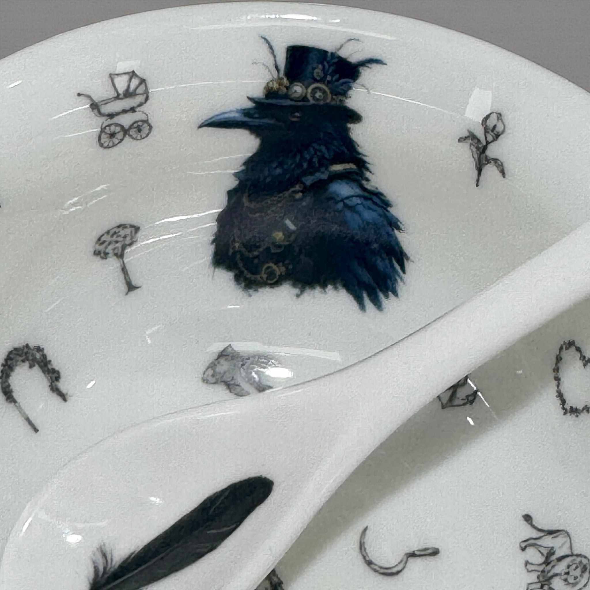 Decorative plate with a black bird illustration wearing a top hat on a white background.